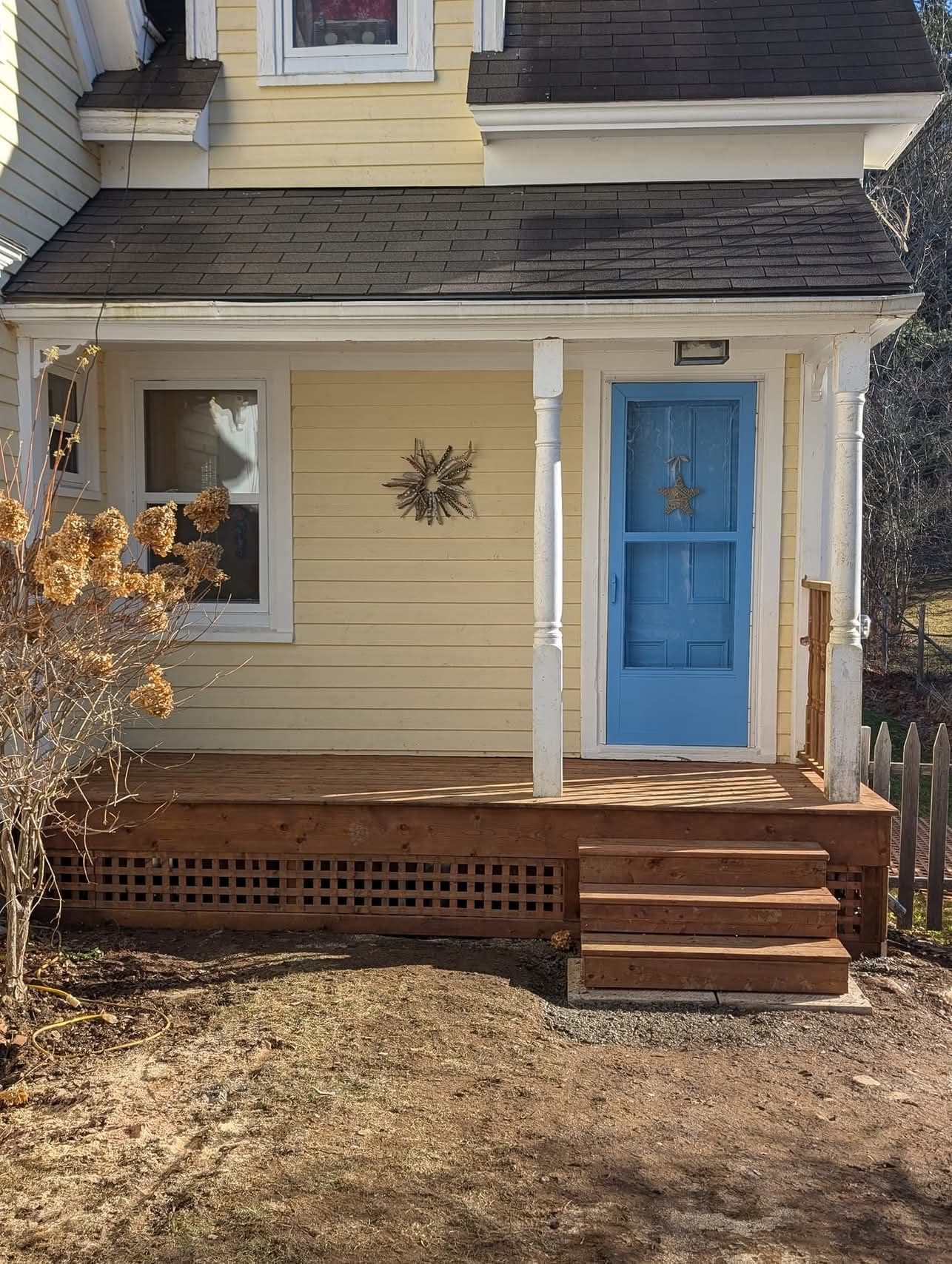 View of a freshly painted yellow house with a new deck